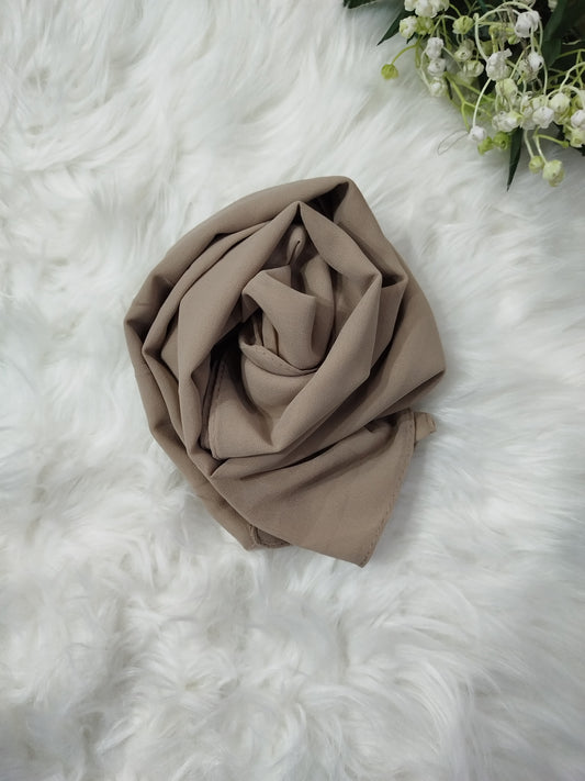 Brown fabric roll on a white fluffy surface with greenery