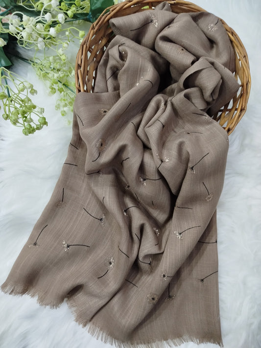 Brown scarf with embroidery in a wicker basket on a white background