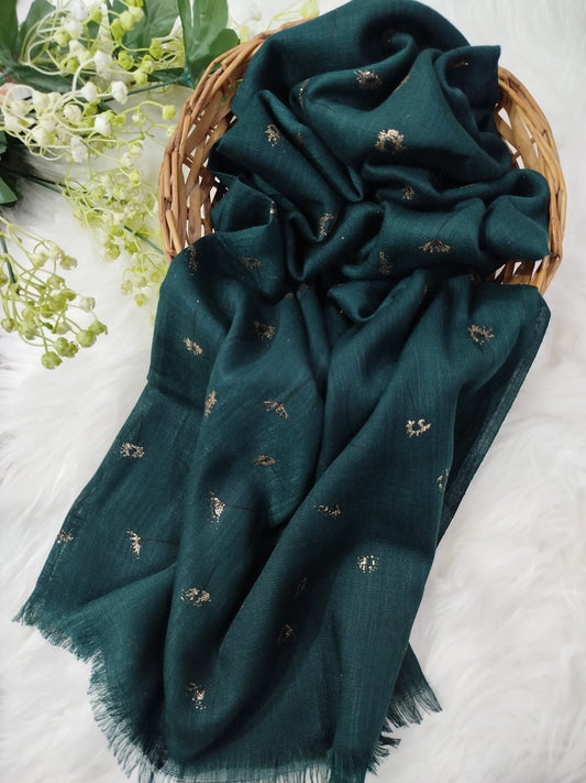 Dark green scarf with small patterns draped over a woven basket on a light background